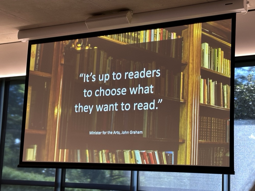A slide with a photo of books and a quote that reads, "It's up to readers to choose what they want to read." Minister for the Arts, John Graham