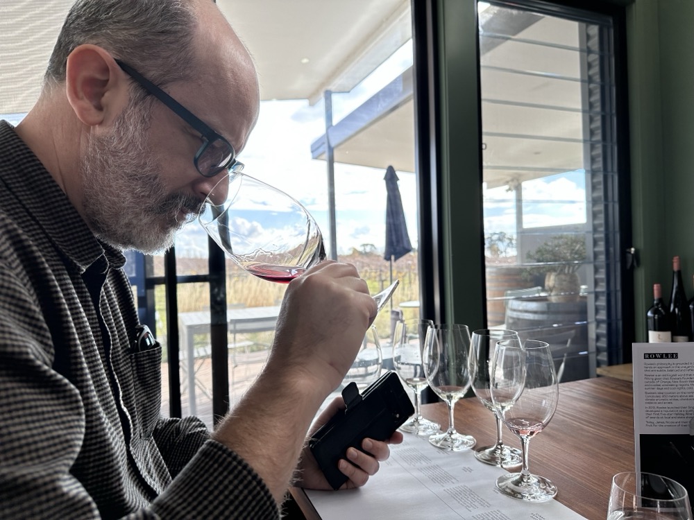 A bearded man smelling a glass of wine
