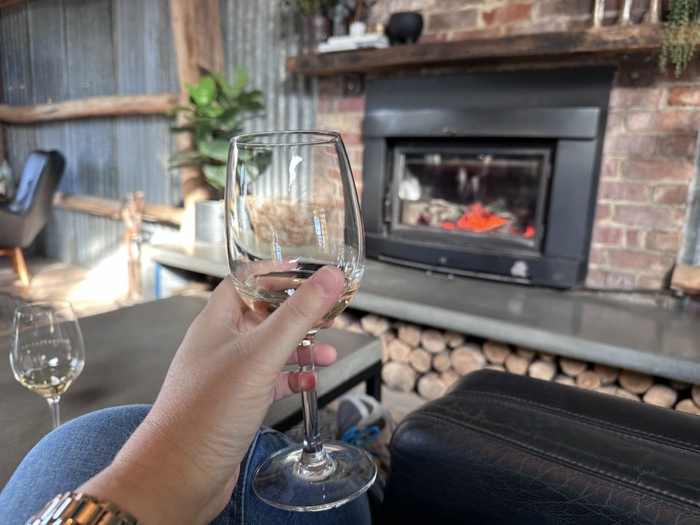 A person with a wineglass in front of a fireplace