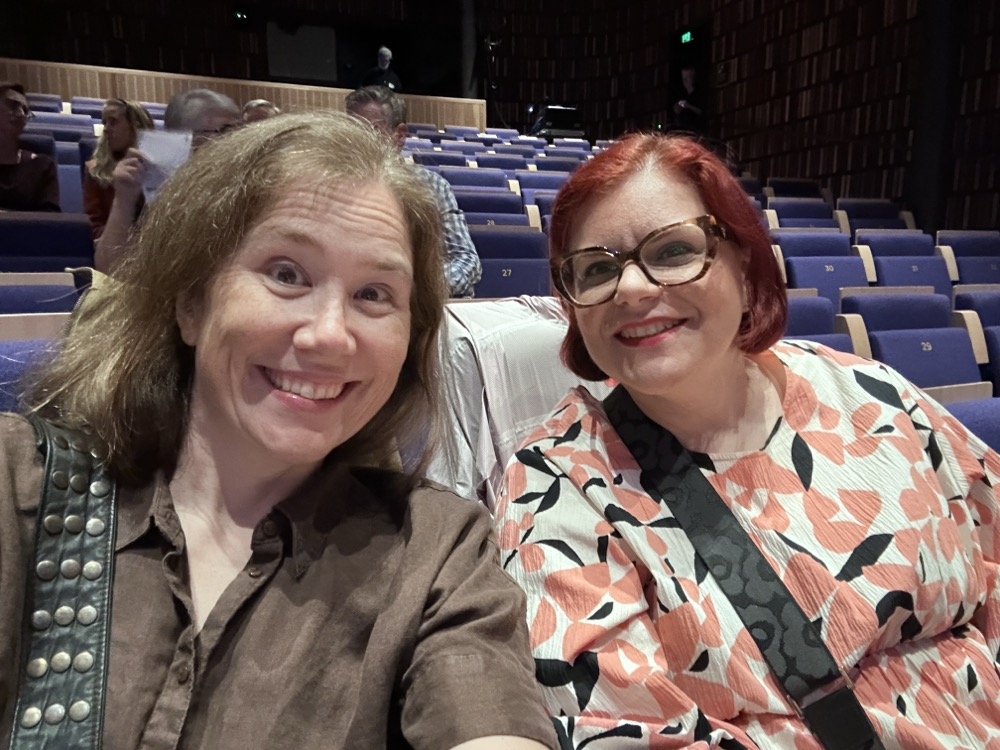 Two middle-aged women sitting in an auditorium