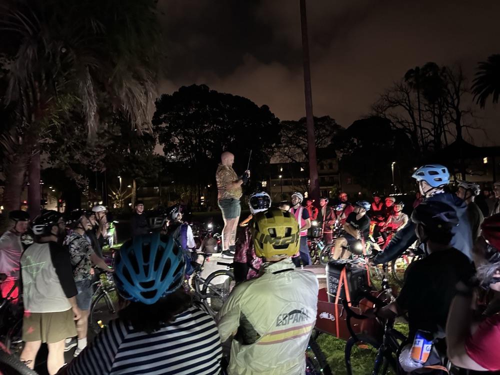 A crowd of cyclists in a park at night